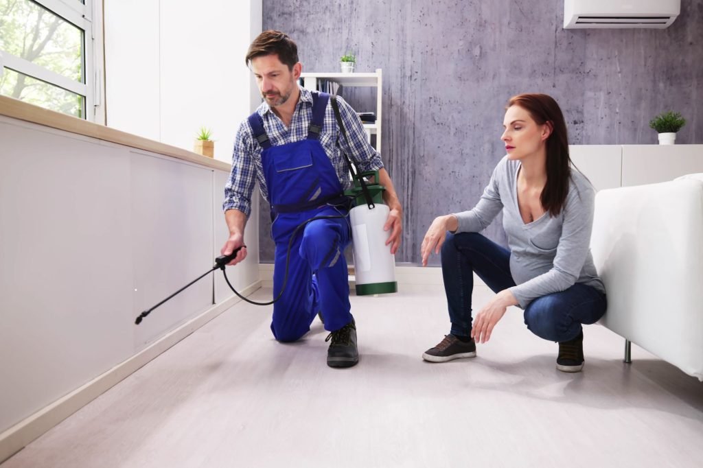 A man and woman using pest control spray to manage ticks and fleas in Honolulu, HI.